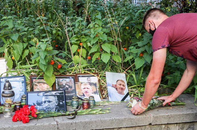 03 August 2021, Ukraine, Kiev: A man lays flowers by the portraits of Belarusian opposition activist activist and Head of the Belarusian House in Ukraine Vitaly Shishov during a protest in his memory outside the Belarus Embassy in Kiev. Shishov was foun