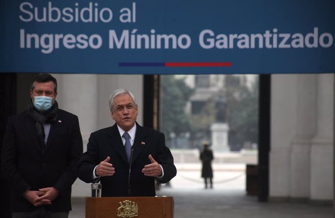 Archivo - 29 May 2020, Chile, Santiago: Chilean President Sebastian Pinera (C) and Social Development Minister Sebastian Sichel speak during a press conference to announce the payment of a guaranteed minimum income subsidy to around 700,000 workers in t