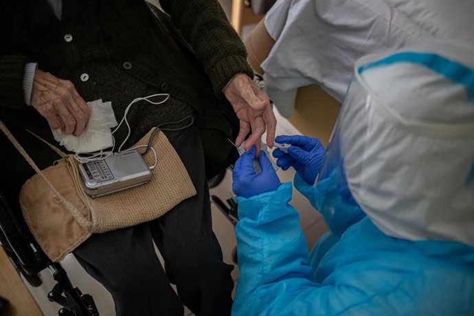 Archivo - Un voluntario de la ONG Proactiva Open Arms realiza un test rápido de Covid-19 extrayendo sangre a un residente 