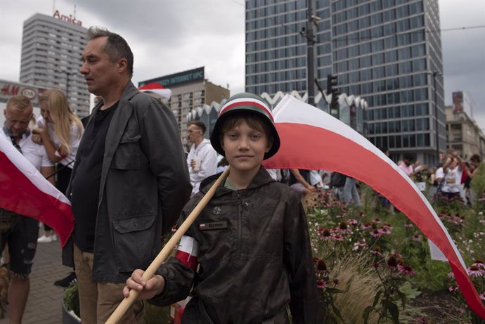 01 August 2021, Poland, Warsaw: A boy wearing a WWII military helmet and holding a Polish flag takes part in the 77th anniversary of the Warsaw uprising, a major World War II operation, in the summer of 1944, by the Polish underground resistance, led by