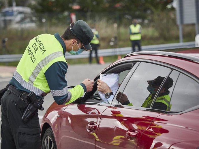 Archivo - Un agente de la Guardia Civil de Tráfico comprueba la documentación de un conductor en un control policial, en una imagen de archivo.