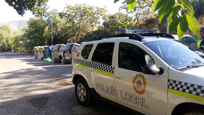 Vehículo de la Policía Local junto a una zona con contenedores.