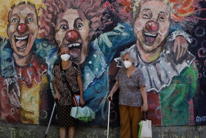 Archivo - Dos mujeres con mascarilla ante un mural en Caracas