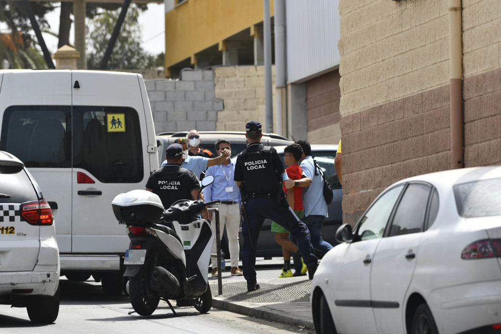 Varios agentes y vehículos de la Policía Local de Ceuta acompañan a menores no acompañados hacia una furgoneta, en las inmediaciones del Polideportivo Santa Amelia, este 13 de agosto 