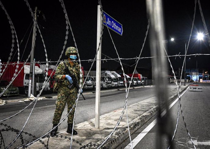 Archivo - 10 May 2020, Malaysia, Petaling Jaya: An Army member stands behind barbed wire fences in the Othman Road Market area. Restrictions aimed at reducingthe spread of the new coronavirus in Malaysia will remain in place for another month. Photo: I