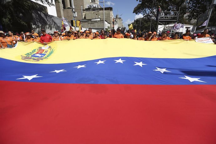Archivo - 10 February 2020, Venezuela, Caracas: Supporters of the government of incumbent Venezuelan President Nicolas Maduro march with a large Venezuelan flag during a protest against the announcement of new sanctions by the United States against teh 