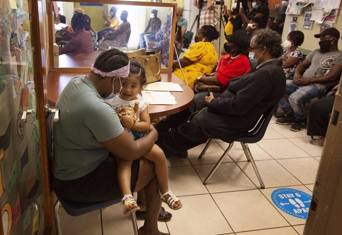 Archivo - 24 May 2021, US, Miami: Julie Jean (L), an undocumented immigrant from Haiti, holds her 2-year-old daughter, Maria J. Tellez while listening to a press conference regarding the Biden administration's redesignation of Temporary Protected Status