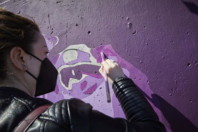 Archivo - Una mujer participa en la tarea de pintar de nuevo el mural feminista de Unlogic Crew junto a la estación de Getafe Central, en Getafe, Madrid (España), a 14 de marzo de 2021. Los creadores del mural feminista de Ciudad Lineal, el colectivo Un