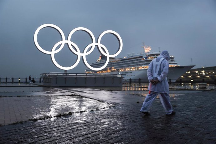 Archivo - 09 July 2021, Japan, Yokohama: A security guard in rain gear walks past an illuminated sculpture of the Olympic rings, ahead of the opening of the Tokyo 2020 Olympic Games. Photo: Stanislav Kogiku/SOPA Images via ZUMA Wire/dpa