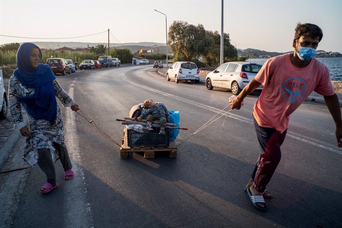 Archivo - Two Afghan parents move their few remaining belongings from the old camp in Moria with their baby on a pallet as a cart, in Lesbos, Greece, on 21 September 2020. Greece started yesterday to move 700 migrants from Lesbos to Athens after they we