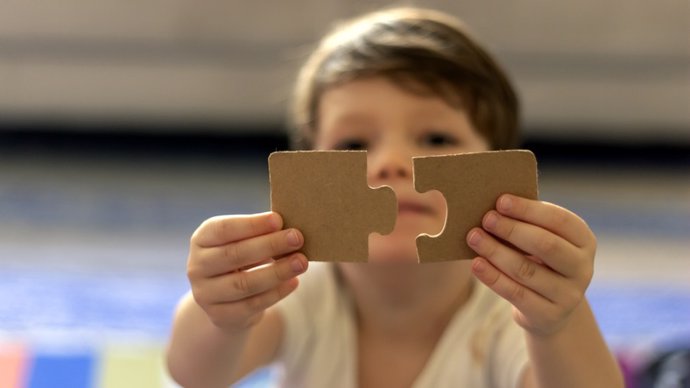 Archivo - Niño con utismo sujetando un puzzle