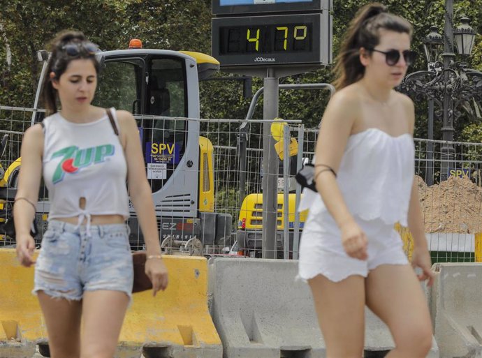 Archivo - Dos mujeres pasan junto a un termómetro que marca 47 durante un día de alerta roja por altas temperaturas, a 12 de julio de 2021, en Valencia