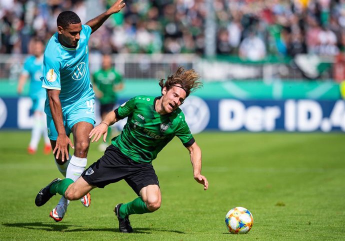08 August 2021, North Rhine-Westphalia, Muenster: Wolfsburg's Maxence Lacroix (L) and Muenster's Jules Schwadorf in action during the German DFB Cup first round soccer match between Preussen Muenster and VfL Wolfsburg. Photo: Guido Kirchner/dpa - IMPORT