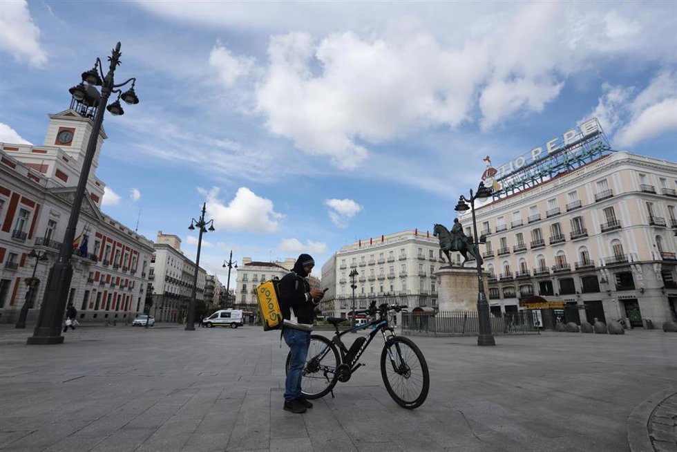 Archivo - Un repartidor de la empresa Glovo mira su teléfono en la Puerta del Sol