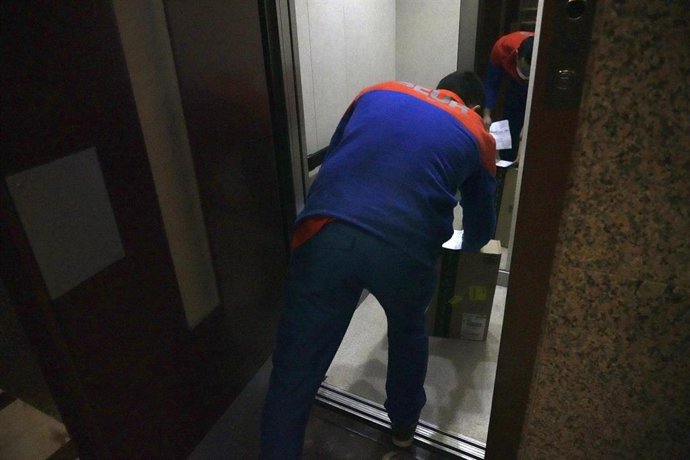 Archivo - Un repartidor dejando un paquete en el ascensor de un edificio 