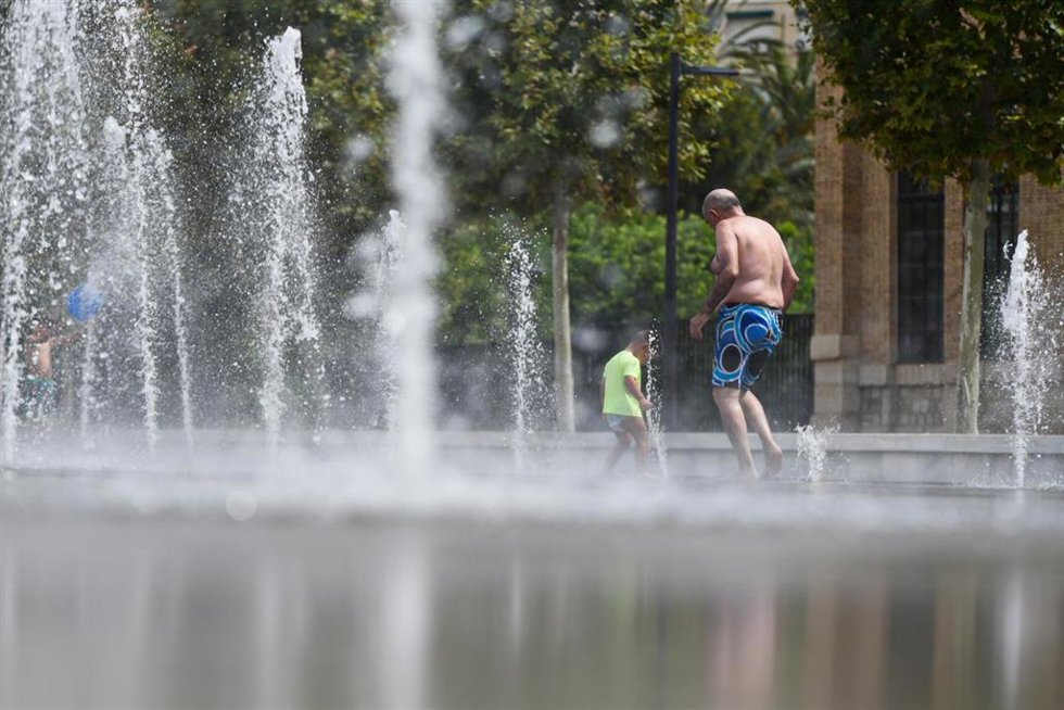 Dos personas se refrescan en una fuente durante la última ola de calor (Archivo)