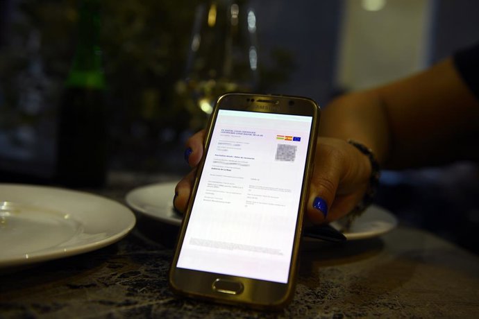 Certificado digital de vacunación de una clienta de La Rioja en el casco histórico de Orense durante el primer día de restricciones en la hostelería de los municipios que se encuentren en niveles máximos y altos de restricciones por coronavirus, a 24 de