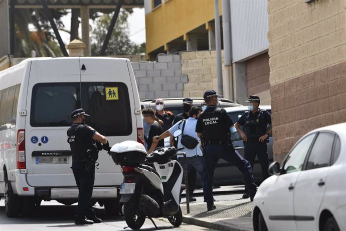 Varios agentes y vehículos de la Policía Local de Ceuta acompañan a menores no acompañados hacia una furgoneta