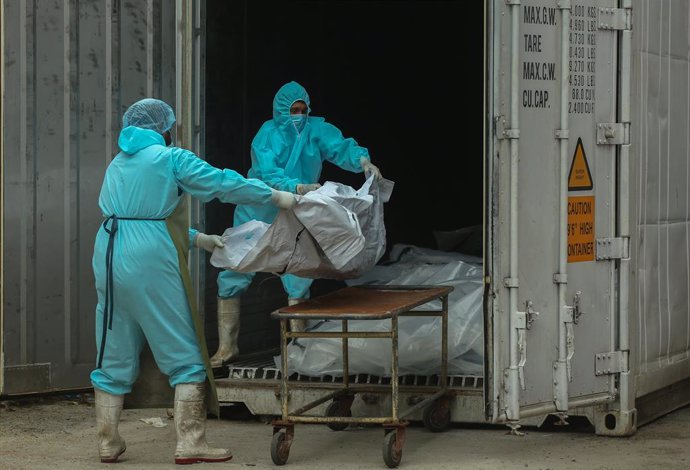 20 August 2021, Sri Lanka, Colombo: Helath workers in protective suits carry a body of a Coronavirus victim from a freezer storage to a trolley at the Institute of Forensic Medicine & Toxicology in Colombo. Photo: Pradeep Dambarage/ZUMA Press Wire/dpa
