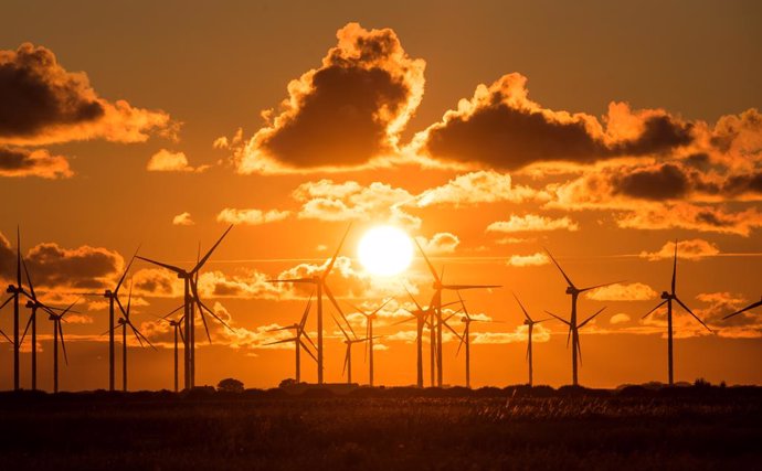03 August 2021, Schleswig-Holstein, Bredstedt: The sun sets behind a wind farm with wind turbines at Bredstedter Koog. Photo: Daniel Bockwoldt/dpa
