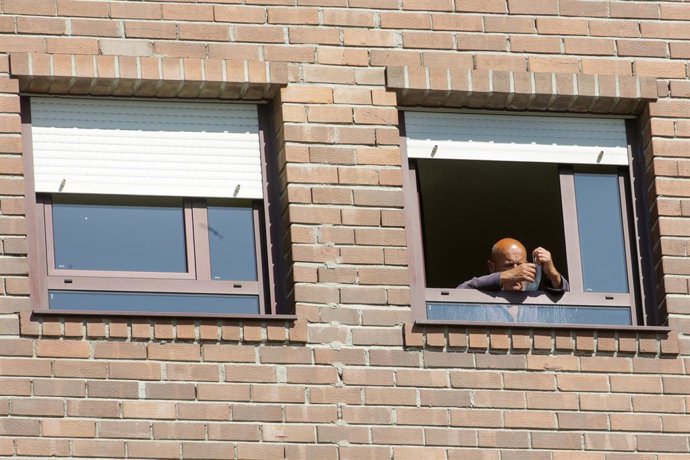 Un anci colloca el seu mascarilla en la finestra de la seva habitació de la residncia de majors