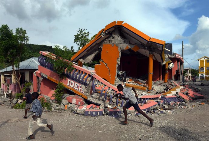 19 August 2021, Haiti, Les Cayes: Children plays in front of a damaged house after a massive earthquake in Les Cayes. Photo: Carol Guzy/ZUMA Press Wire/dpa
