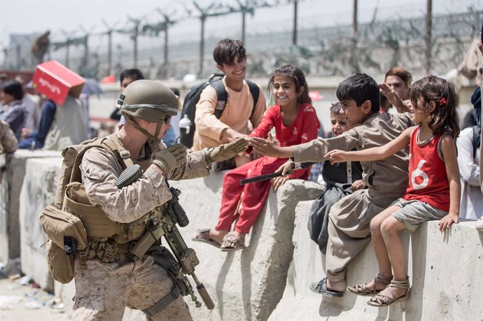 20 August 2021, Afghanistan, Kabul: A US Marine soldier plays with children as Afghan civilians wait to board an aircraft during the evacuation process at Hamid Karzai International Airport. Photo: Samuel Ruiz/U.S. Marine Corps via ZUMA Wire/dpa