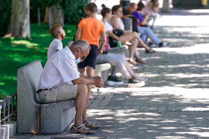 Un anciano con mascarilla sentado en un banco