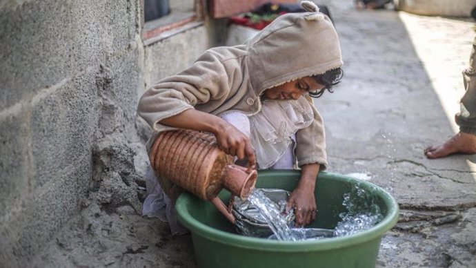Una niña de 14 años lava los platos en un campo de desplazados en Yemen.