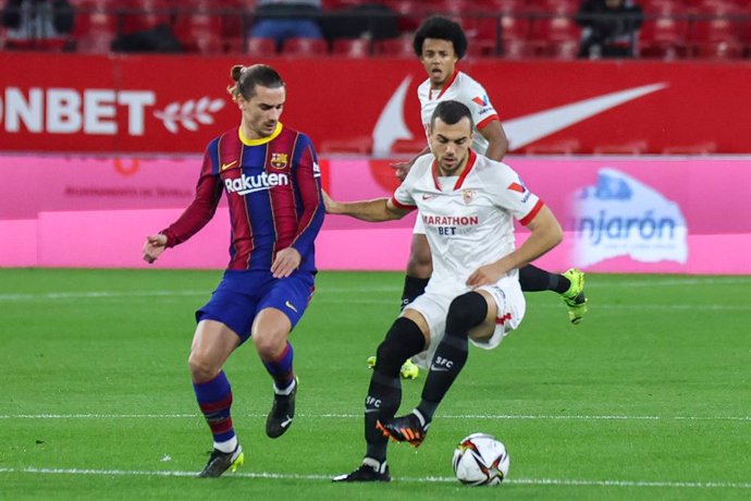 Archivo - 10 February 2021, Spain, Seville: Barcelona's Antoine Griezmann (L) and Sevilla's Joan Jordan battle for the ball during the Spanish Copa del Rey (King's Cup) semi-final leg 1 soccer match between Sevilla FC and FC Barcelona at Ramon Sanchez-P