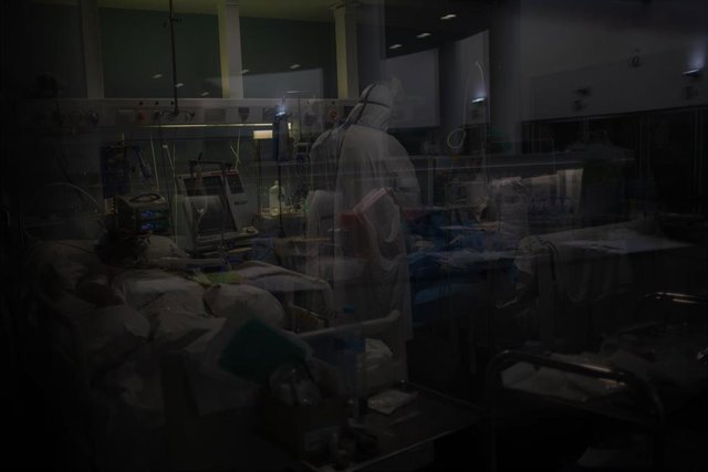 Archivo - Trabajadores sanitarios protegidos atienden a un paciente en una UCI (Archivo)