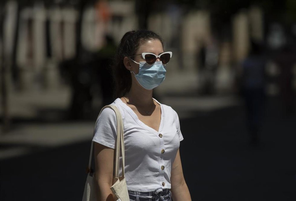 Archivo - Una mujer con mascarilla y gafas de sol en imagen de archivo