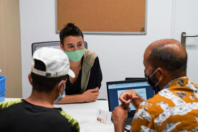 Una profesional atiende a dos personas en el nuevo centro de servicios sociales que ha abierto el Ayuntamiento en la calle Casp de Barcelona.
