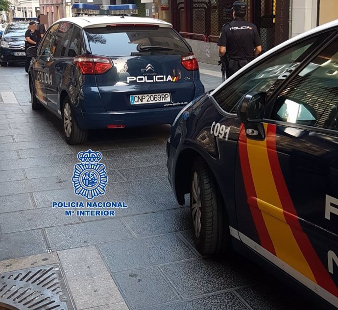 Archivo - Agentes de la Policía Nacional junto a dos coches patrulla