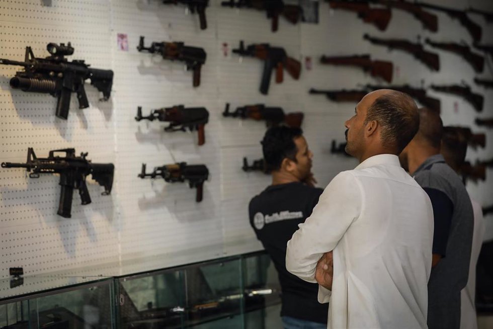 Archivo - Un cliente examina diferentes modelos de fusiles rusos Kalashnikov en una feria de armamento
