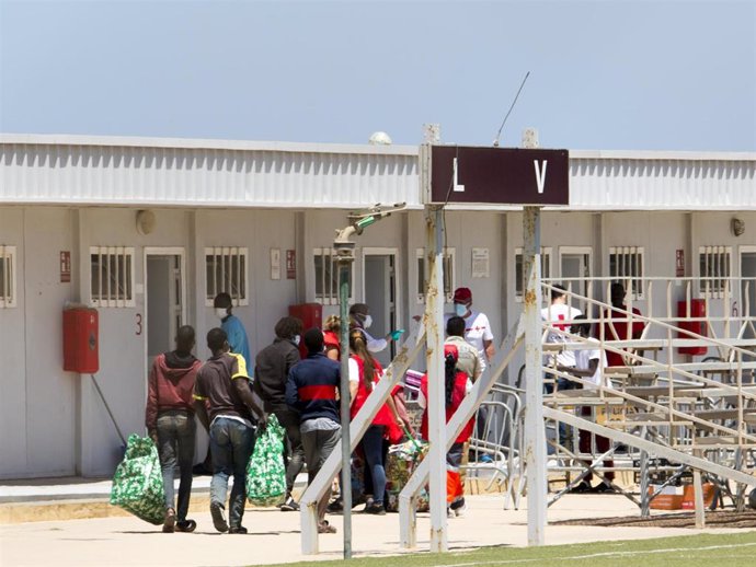 Archivo - Varios migrantes acceden junto a miembros de la Cruz Roja a las instalaciones de la Ciudad del Fútbol del Altos del Real a 18 de mayo de 2021, en Melilla (España). 
