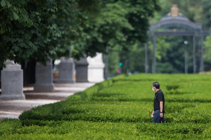 Archivo - Un hombre pasea protegido con mascarilla por el Parque de El Retiro
