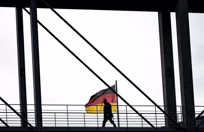 Archivo - 02 November 2020, Berlin: A man crosses the Marie-Elisabeth-Luders-House jetty in front of a German flag. The federal and state governments have decided on a partial lockdown. Photo: Fabian Sommer/dpa