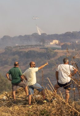 Vecinos de Lucena del Puerto observan el helicóptero del Infoca durante la extinción del incendio forestal que afectó al paraje conocido como El Bosque.