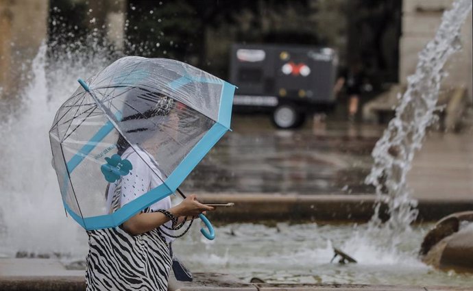 Una persona sostiene un paraguas mientras llueve, a 26 de julio de 2021, en Valencia, Comunidad Valenciana, (España). Para esta jornada, con nivel máximo naranja, se espera cielo nuboso que tenderá a intervalos nubosos al final y viento de componente es