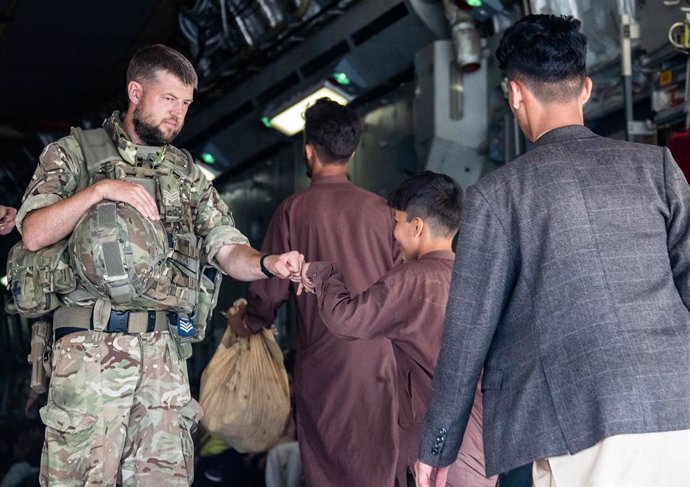 HANDOUT - 23 August 2021, Afghanistan, Kabul: A member of the UK Armed Forces fist-bumps a child evacuee at Kabul airport amid the Taliban takeover. Photo: Lphot Ben Shread/MoD/PA Wire/dpa - ATTENTION: editorial use only and only if the credit mentioned