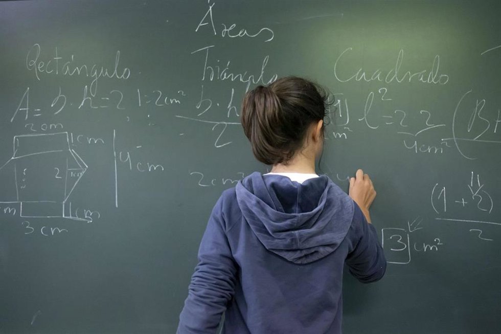 Archivo - Alumna escribe con tiza en una pizarra.