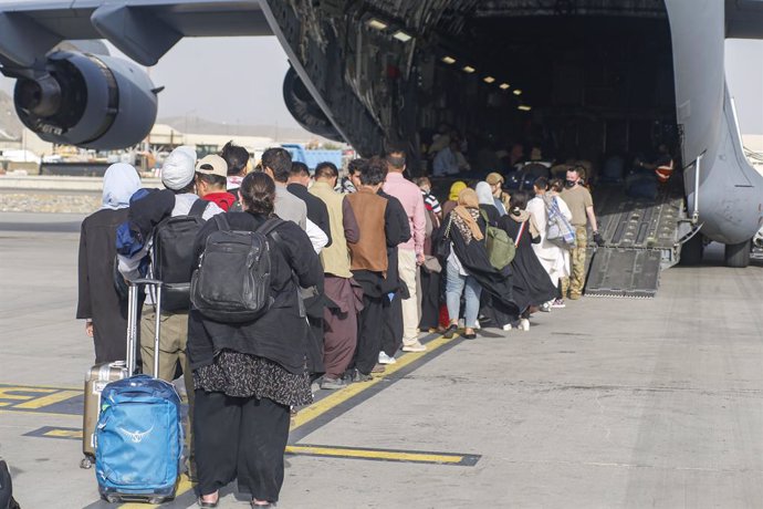 18 August 2021, Afghanistan, Kabul: People stand on the tarmac and board a US C-17 Globemaster III transport plane during their evacuation at Hamid Karzai International Airport in Afghanistan. US soldiers are assisting the State Department with an order