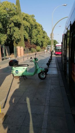Una moto eléctrica de alquiler junto a una parada de bus