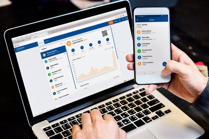 Archivo - Una persona opera en su ordenador y móvil con Bit2Me