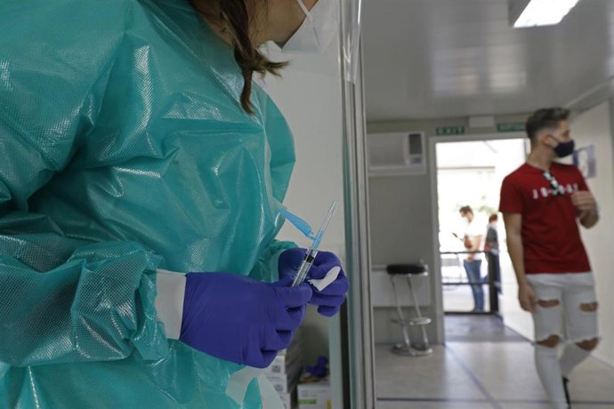 Archivo - Una sanitaria sostiene una jeringuilla en un dispositivo de vacunación.