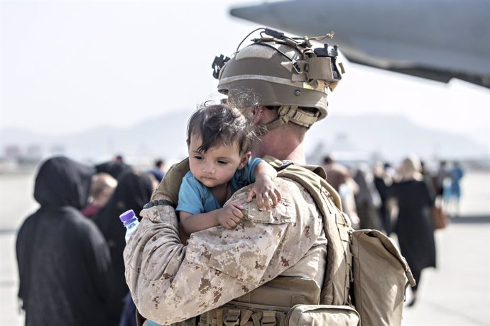 HANDOUT - 22 August 2021, Afghanistan, Kabul: A US marine soldier carries a young boy at the Hamid Karzai International Airport during the evacuation of civilians following the Taliban takeover. Photo: Sgt. Samuel Ruiz/U.S. Marine/Planet Pix via ZUMA Pr