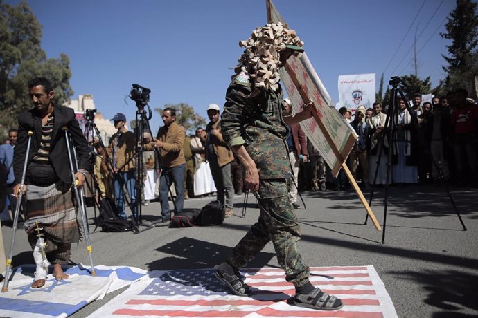 Archivo - 18 January 2021, Yemen, Sanaa: AHouthi soldier walks on a USflag during a protest in front of the USembassy in Sanaa against the United States over its decision to designate the Houthi rebels movement as a foreign terrorist organization. Ph