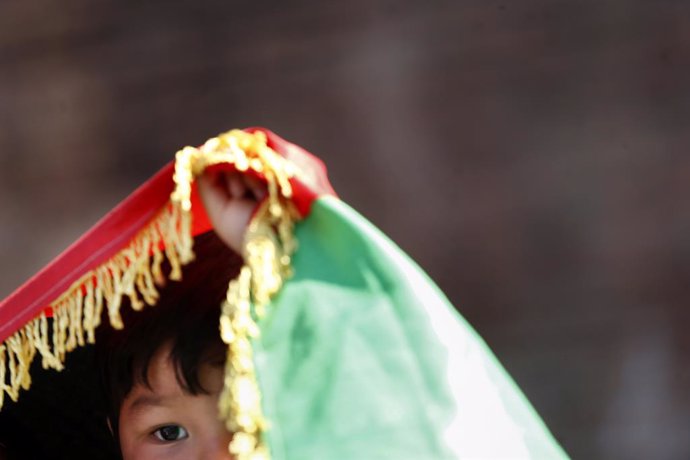 21 August 2021, Italy, Rome: A child stand under a flag oif Afghanistan during a demonstration in Rome's Piazza della Repubblic, in solidarity with Afghanistan after the Taliban takeover. Photo: Cecilia Fabiano/LaPresse via ZUMA Press/dpa
