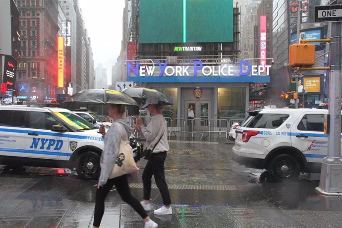 Peatones se protegen de la fuerte lluvia con paraguas mientras cruzan una calle en Times Square 
